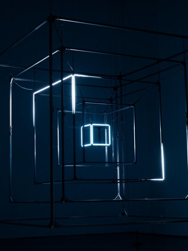 A captivating geometric light installation using cubes and neon lights against a dark background.